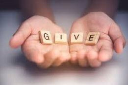 A person is holding wooden blocks in their hands that spell out the word give.