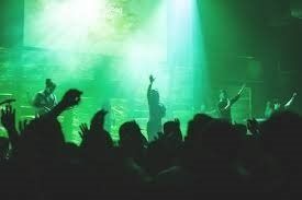 A crowd of people are watching a band perform on stage at a concert.