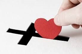 A person is putting a red heart into a black cross.