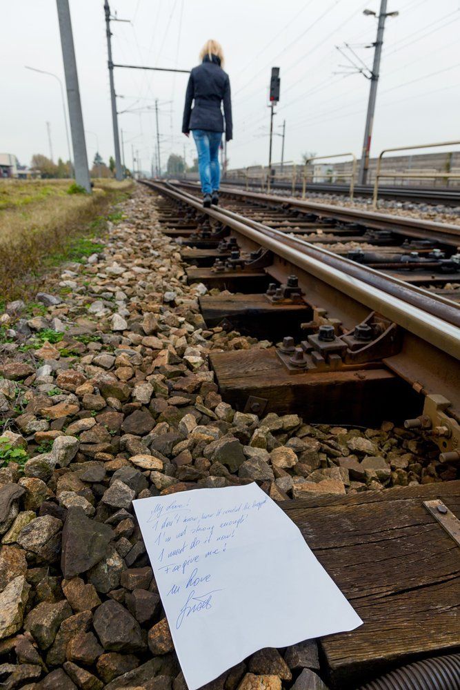 Eine Frau läuft auf Bahngleisen neben einem Stück Papier her.