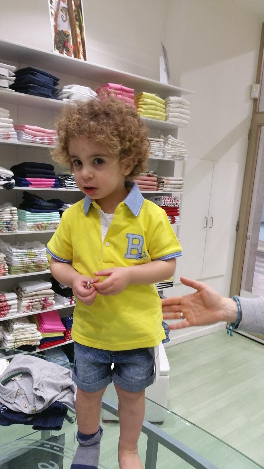 Bambino che prova dei vestiti in un atelier