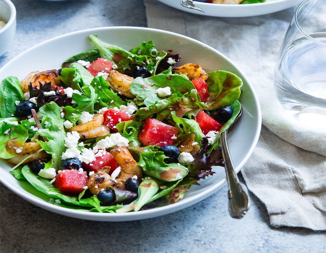 Une salade de pastèque, de myrtilles et de fromage feta dans un bol sur une table.