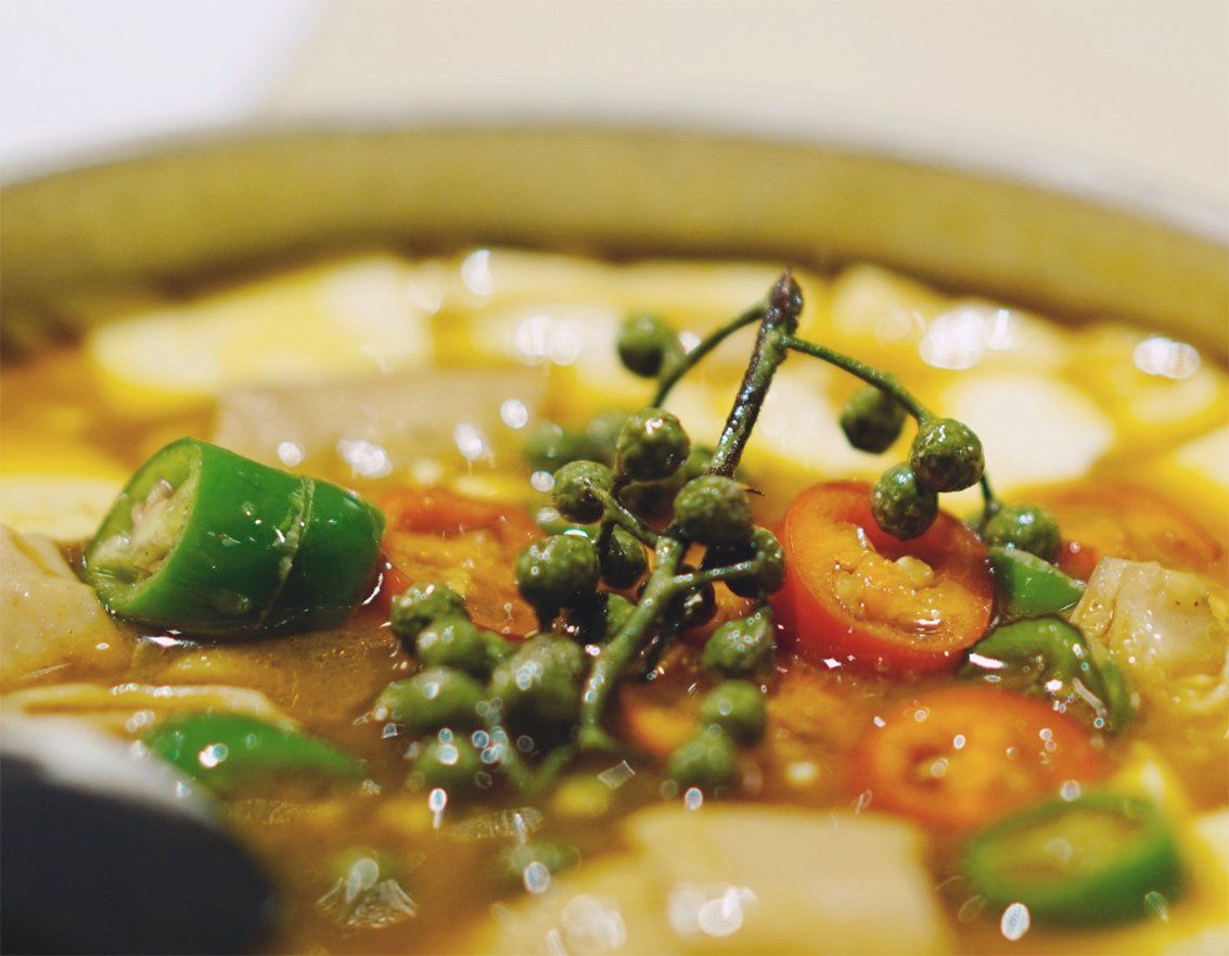 Un gros plan d'un bol de soupe avec des légumes et une cuillère dedans.