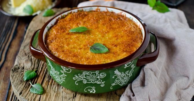 Un pot vert rempli de nourriture est posé sur une table en bois.
