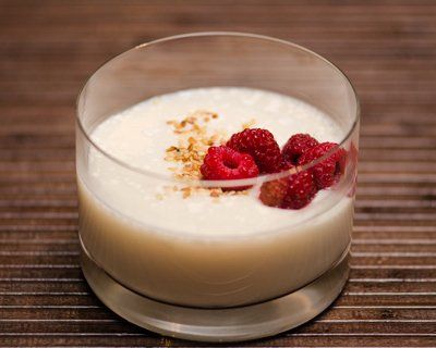 Un verre de yaourt avec des framboises sur une table.