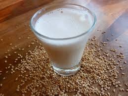 Un verre de lait est posé sur une table en bois à côté des grains.