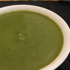 Un gros plan d'un bol de soupe verte sur une table.
