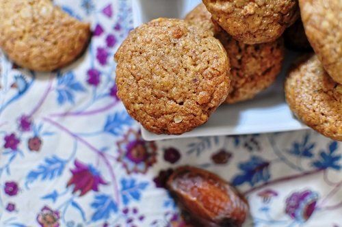 Une assiette blanche garnie de biscuits et de dattes sur une table.