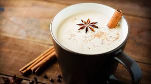 Une tasse de thé chai avec des bâtons de cannelle et de l'anis étoilé sur une table en bois.
