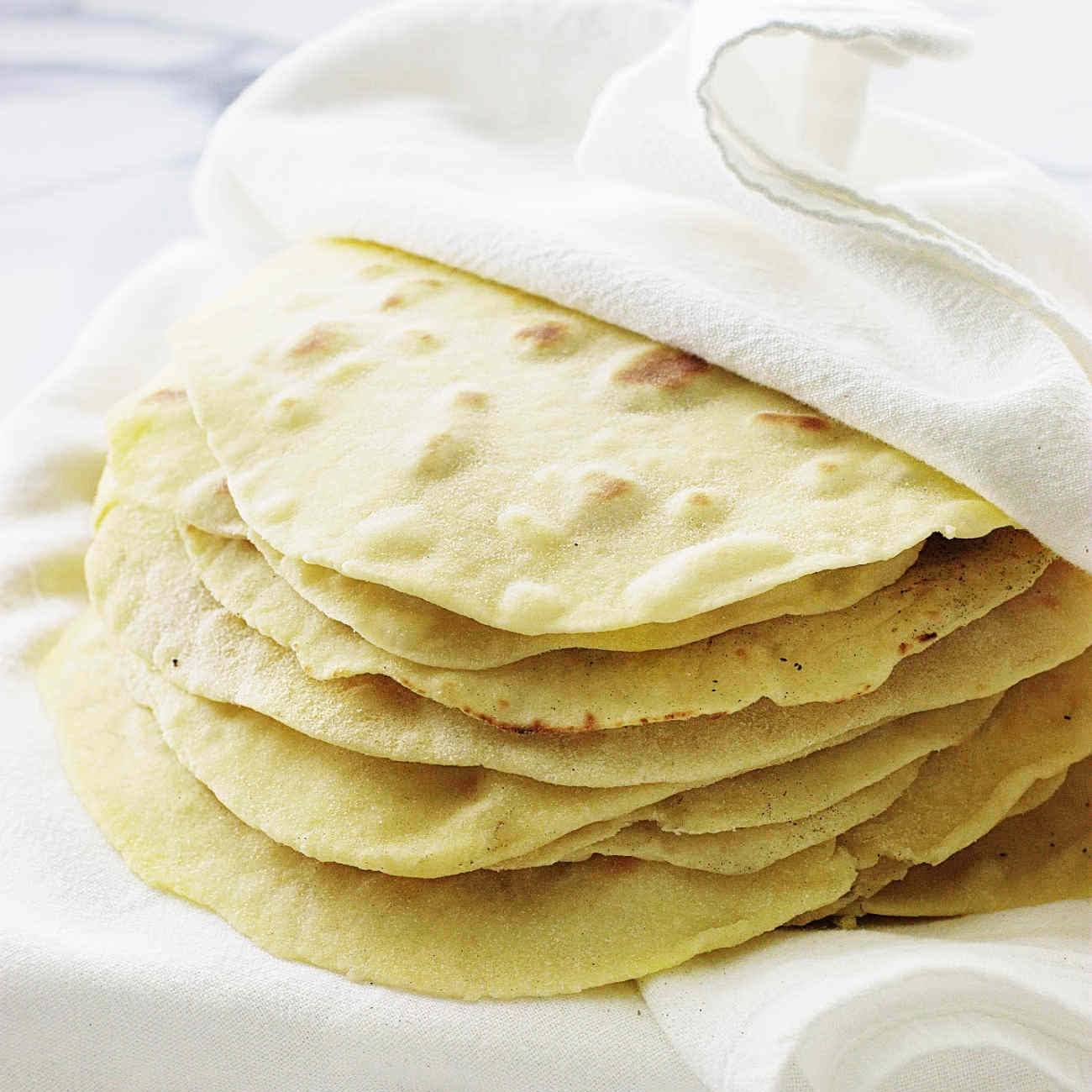 Une pile de tortillas est enveloppée dans un tissu blanc.