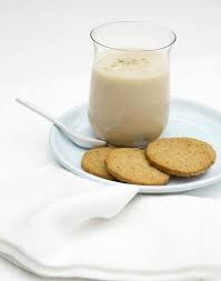 Un verre de lait et des biscuits sur une assiette avec une cuillère.