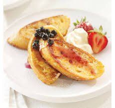 Pain perdu avec fraises et crème fouettée sur une assiette blanche.