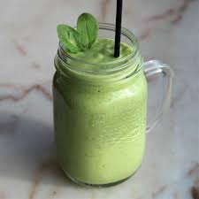 Un smoothie vert dans un pot Mason avec une paille.