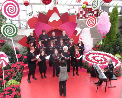 Une chorale chante devant des cannes de bonbon et de la barbe à papa