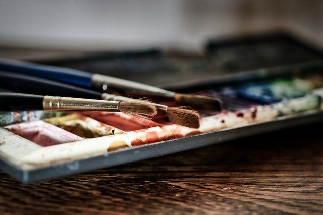 Une palette d'aquarelles et de pinceaux sur une table en bois.