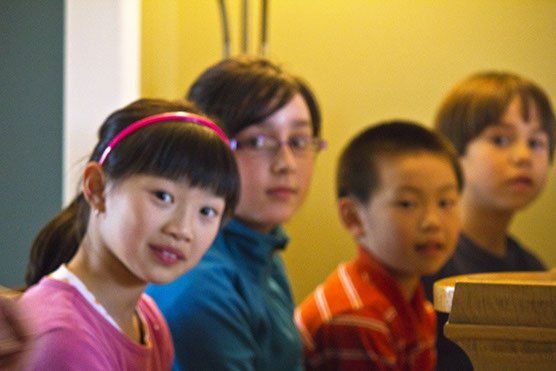 Un groupe d'enfants sont assis en rangée et regardent la caméra