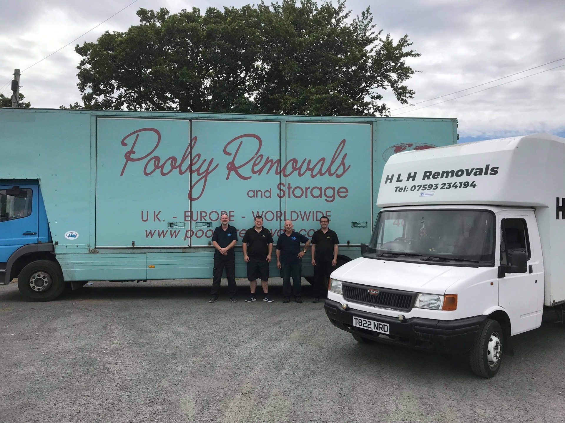 Four men stand between two removal trucks in a parking lot, with “Pooles Removals” on the side.