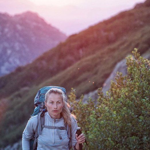 A woman with a backpack is hiking up a mountain.