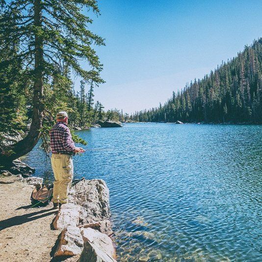 A man is standing on the shore of a lake.