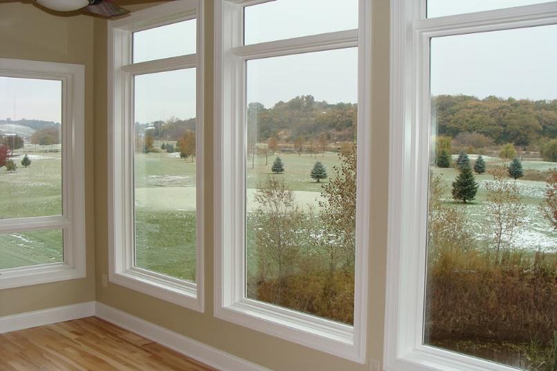 A room with a lot of windows and a view of a golf course.