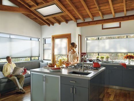 A man is reading a newspaper while a woman prepares food in a kitchen.