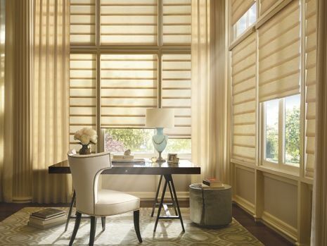 A home office with a desk , chair , lamp and curtains.