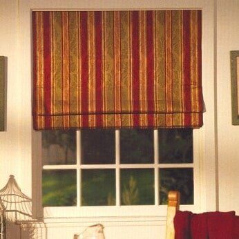 A window with a red and gold striped roman shade