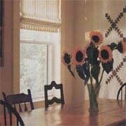 A dining room table with a vase of sunflowers on it.