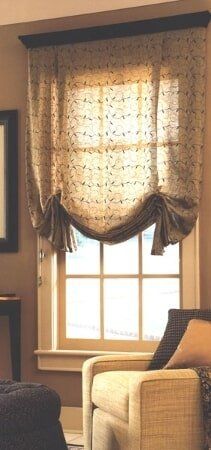 A living room with a couch and a window with a roman shade