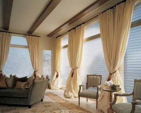 A living room with a couch and chairs and curtains