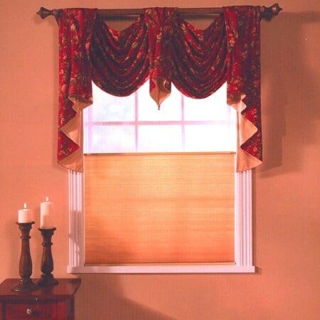 A window with red curtains and candles on a table
