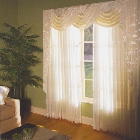 A living room with green walls and white curtains
