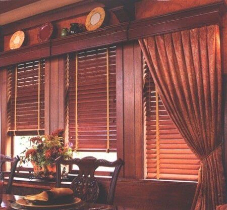 A dining room with wooden blinds and plates on a shelf