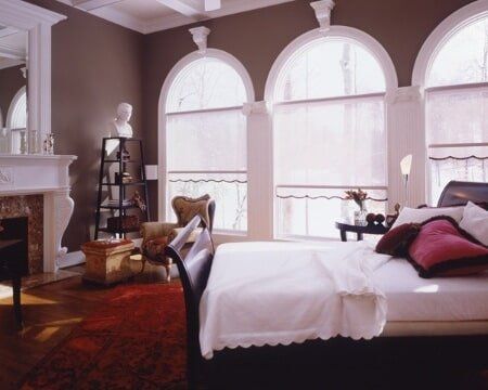 A bedroom with arched windows and a bed