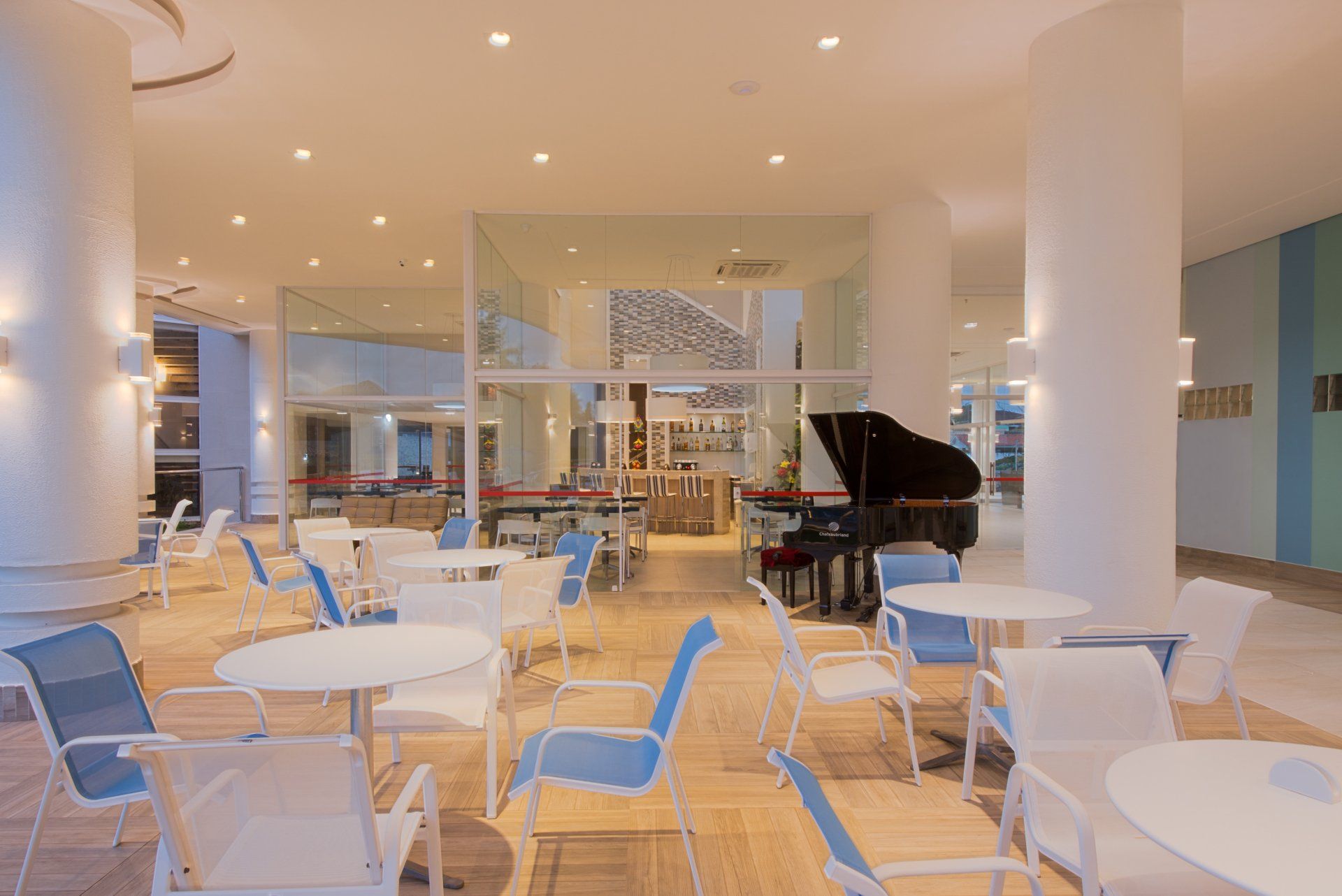 Uma sala grande com mesas e cadeiras e um piano.