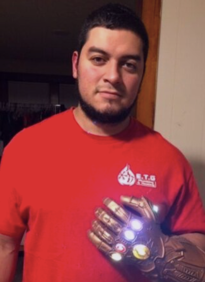 A man in a red shirt is holding a glowing glove