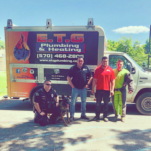 A group of men standing in front of a truck that says e.t.g plumbing & heating