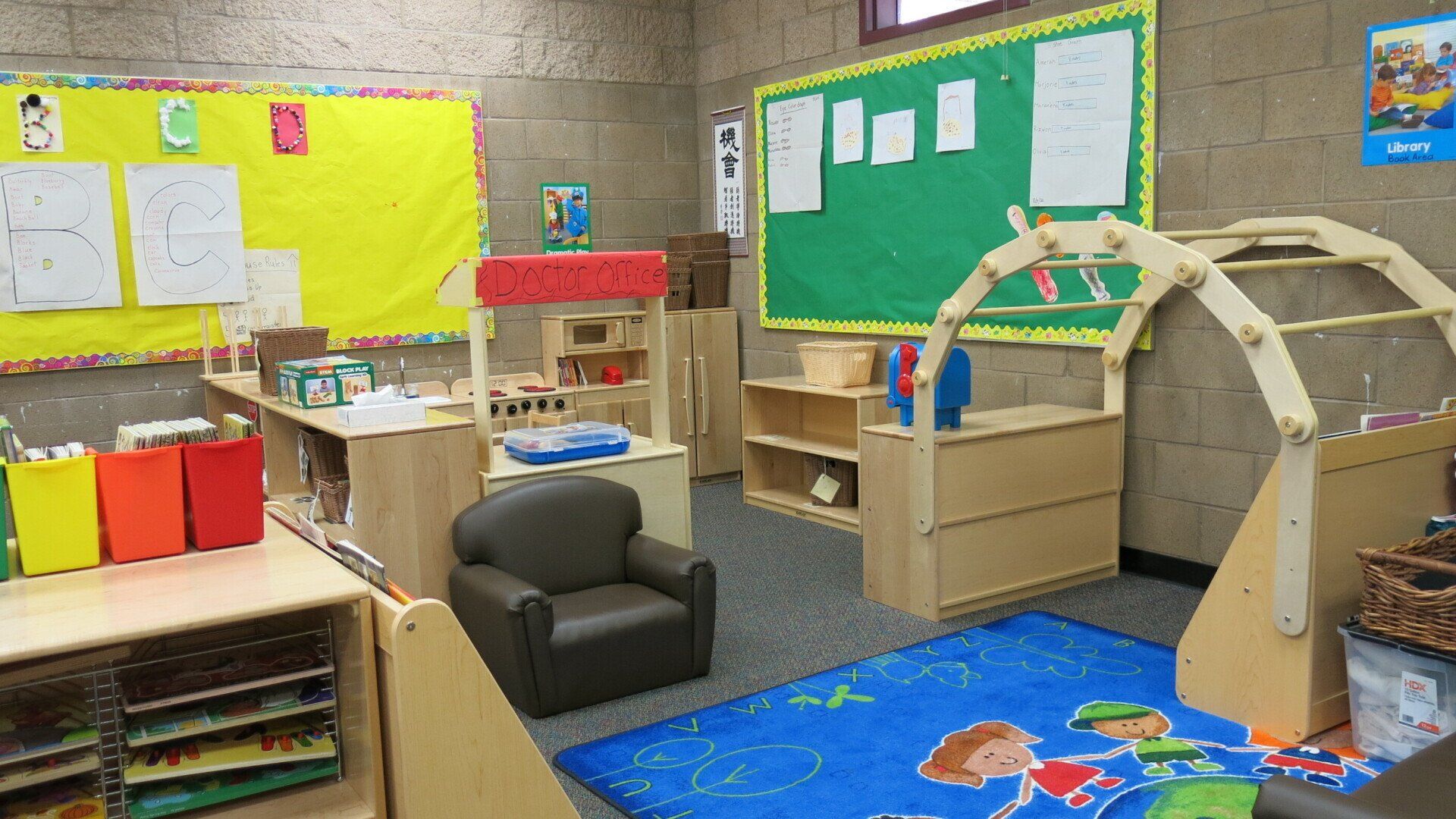 A classroom with a chair a rug and a green board