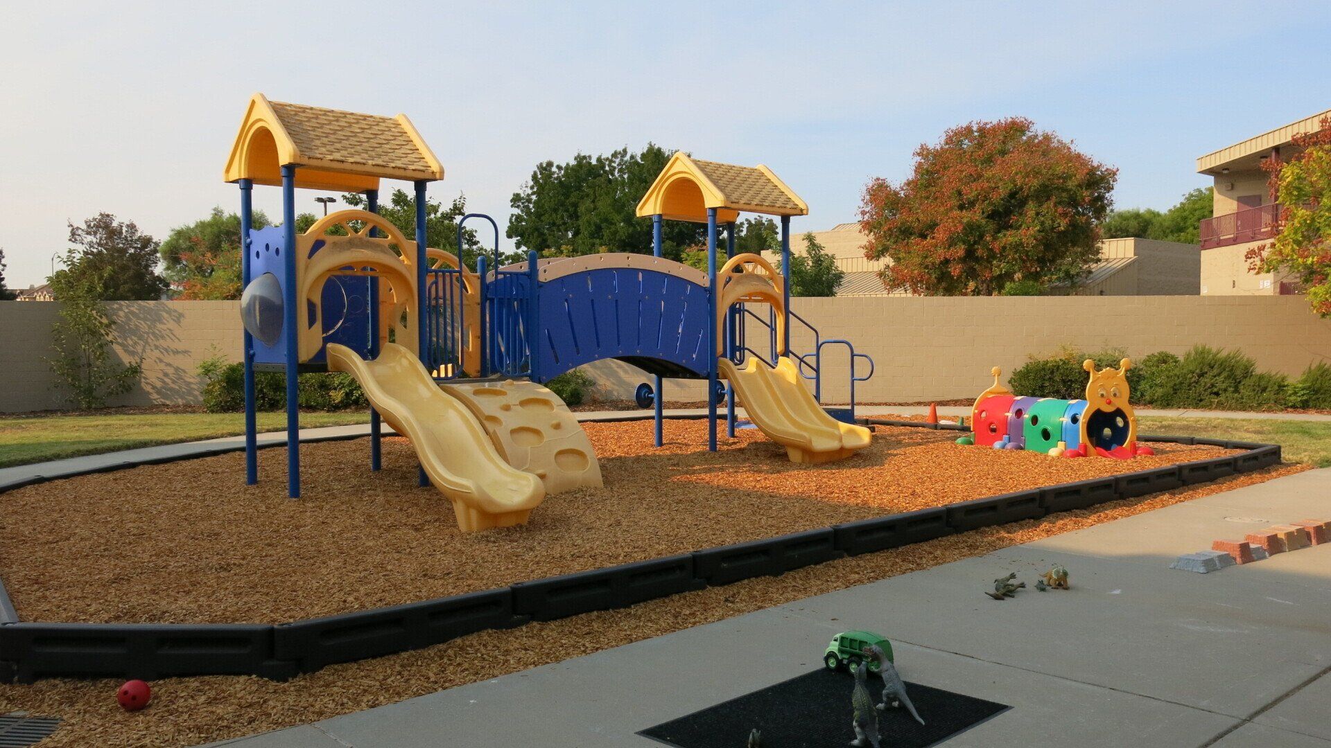 A playground with a blue slide and a yellow slide