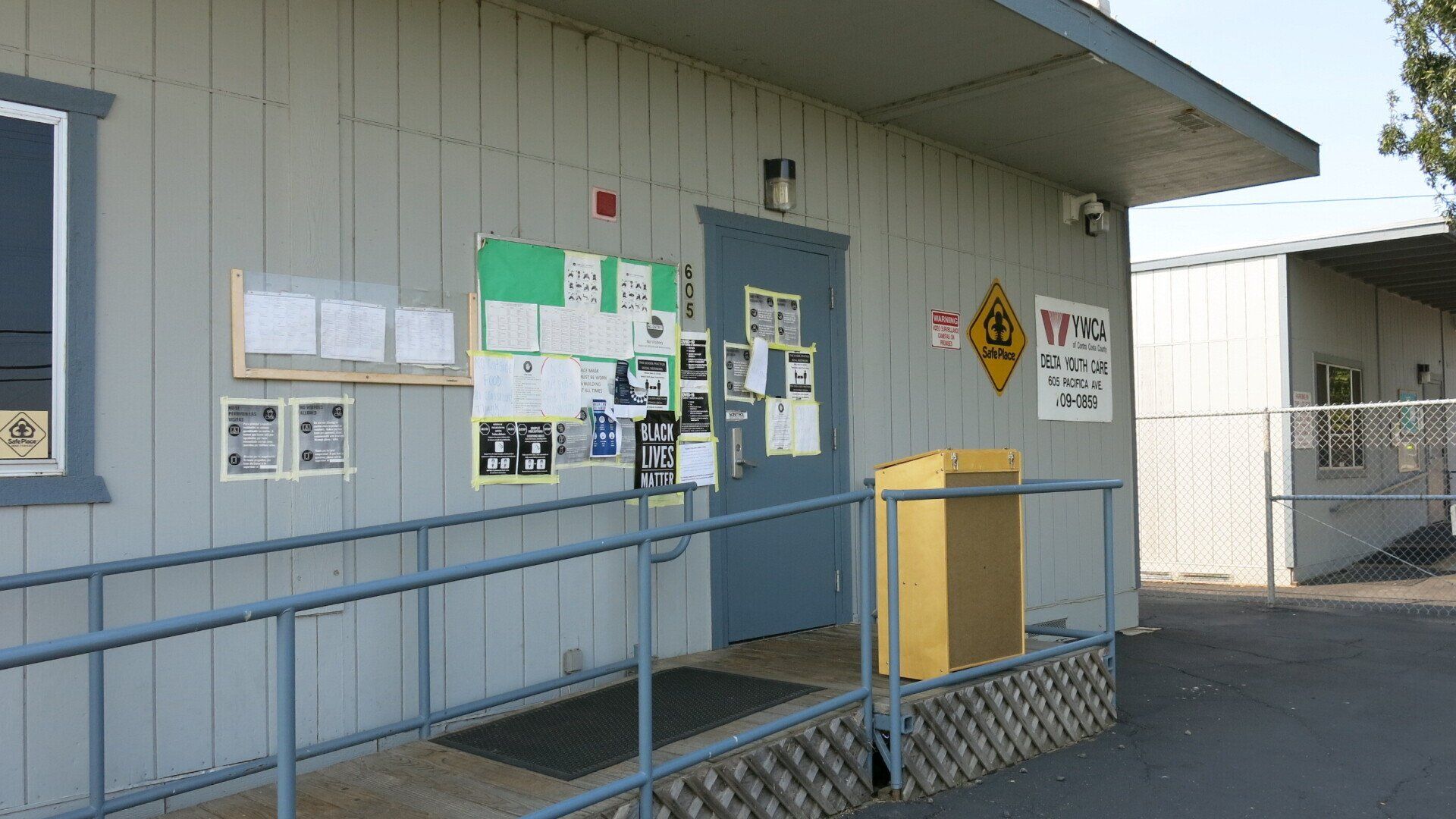 A building with a handicap ramp and a yellow box in front of it.