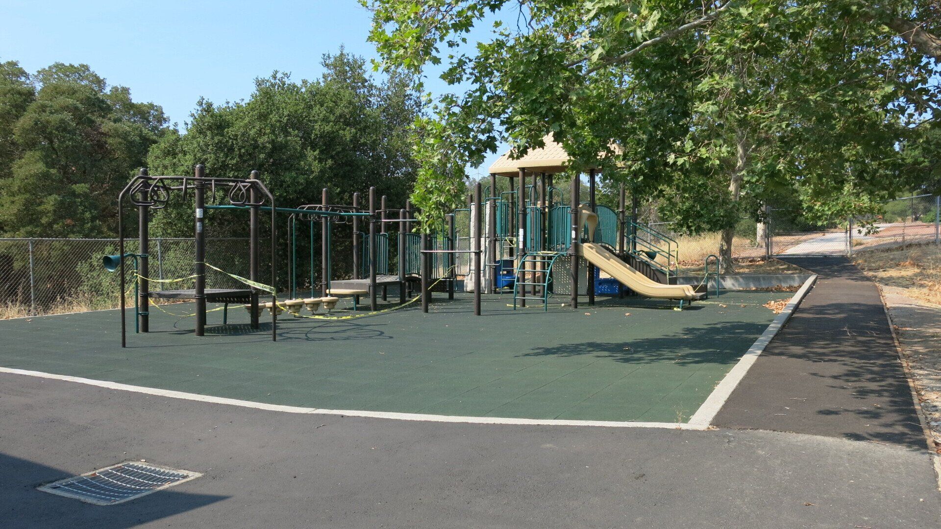 A playground is surrounded by trees on a sunny day