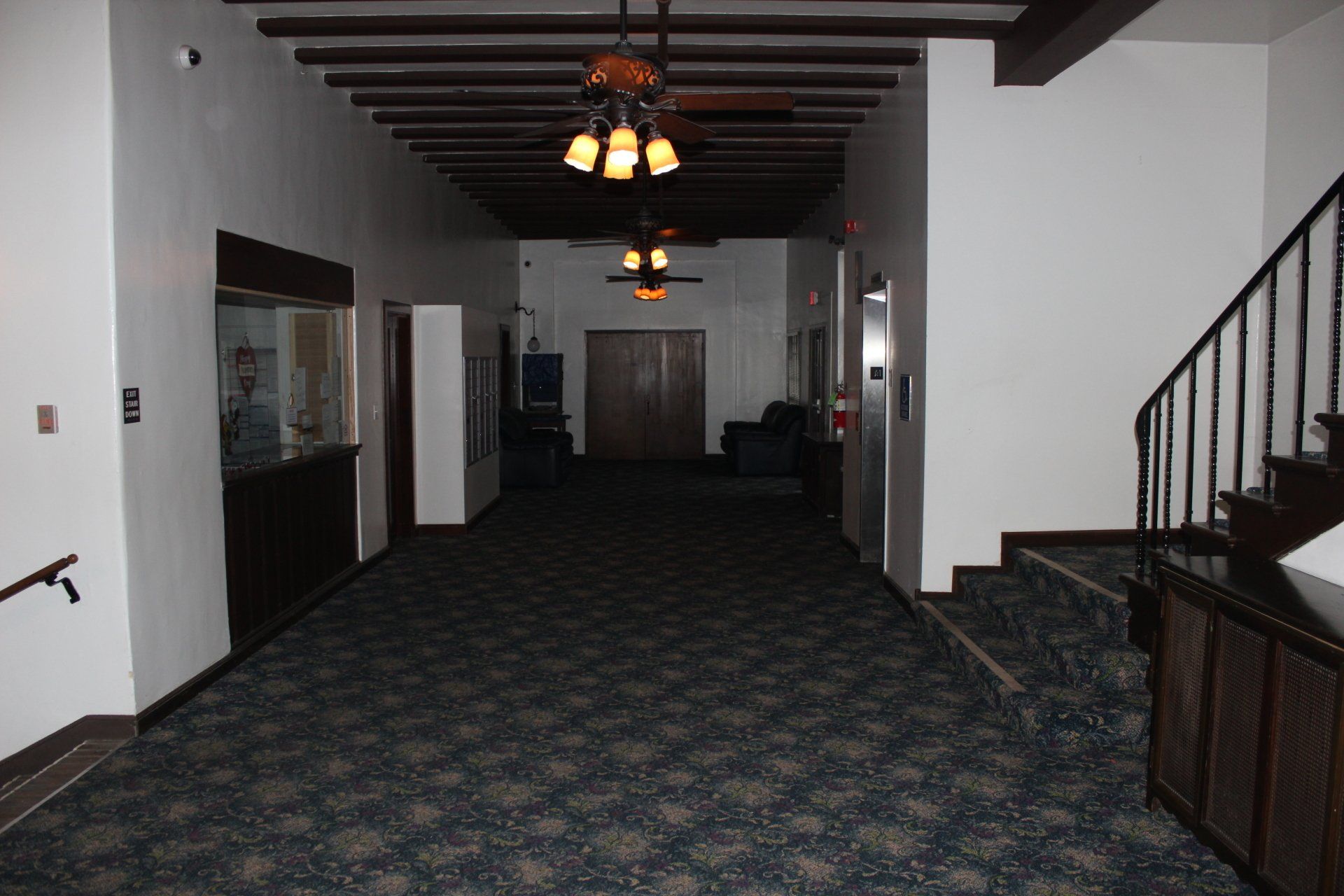 An empty hallway with stairs and a ceiling fan.