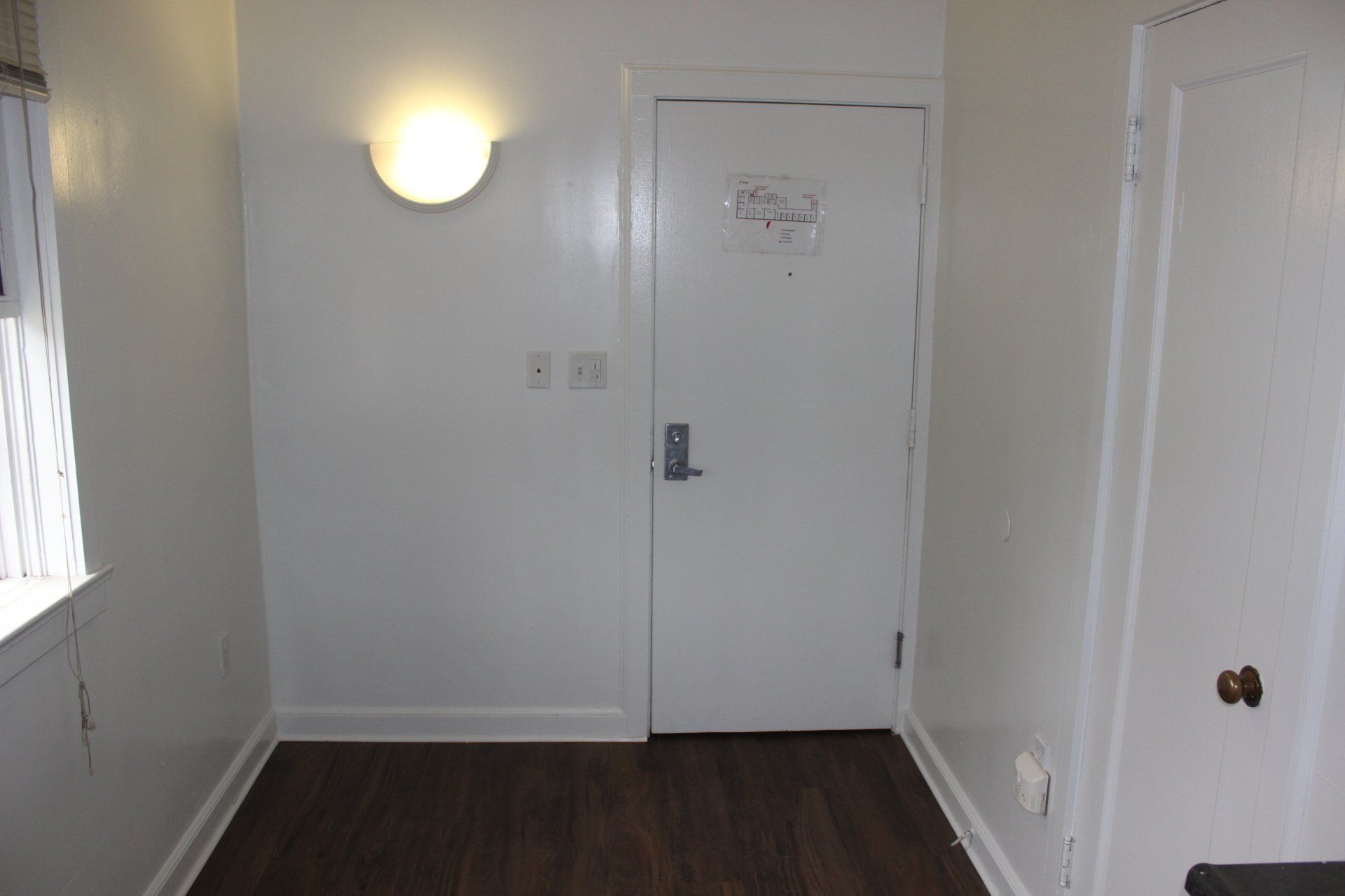 An empty room with a door and a light on the wall.