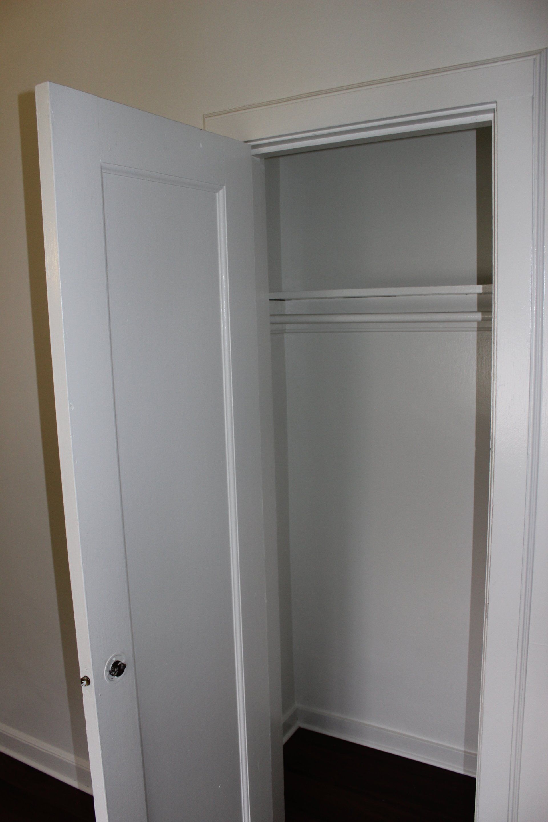 A white closet with a door open in a room.