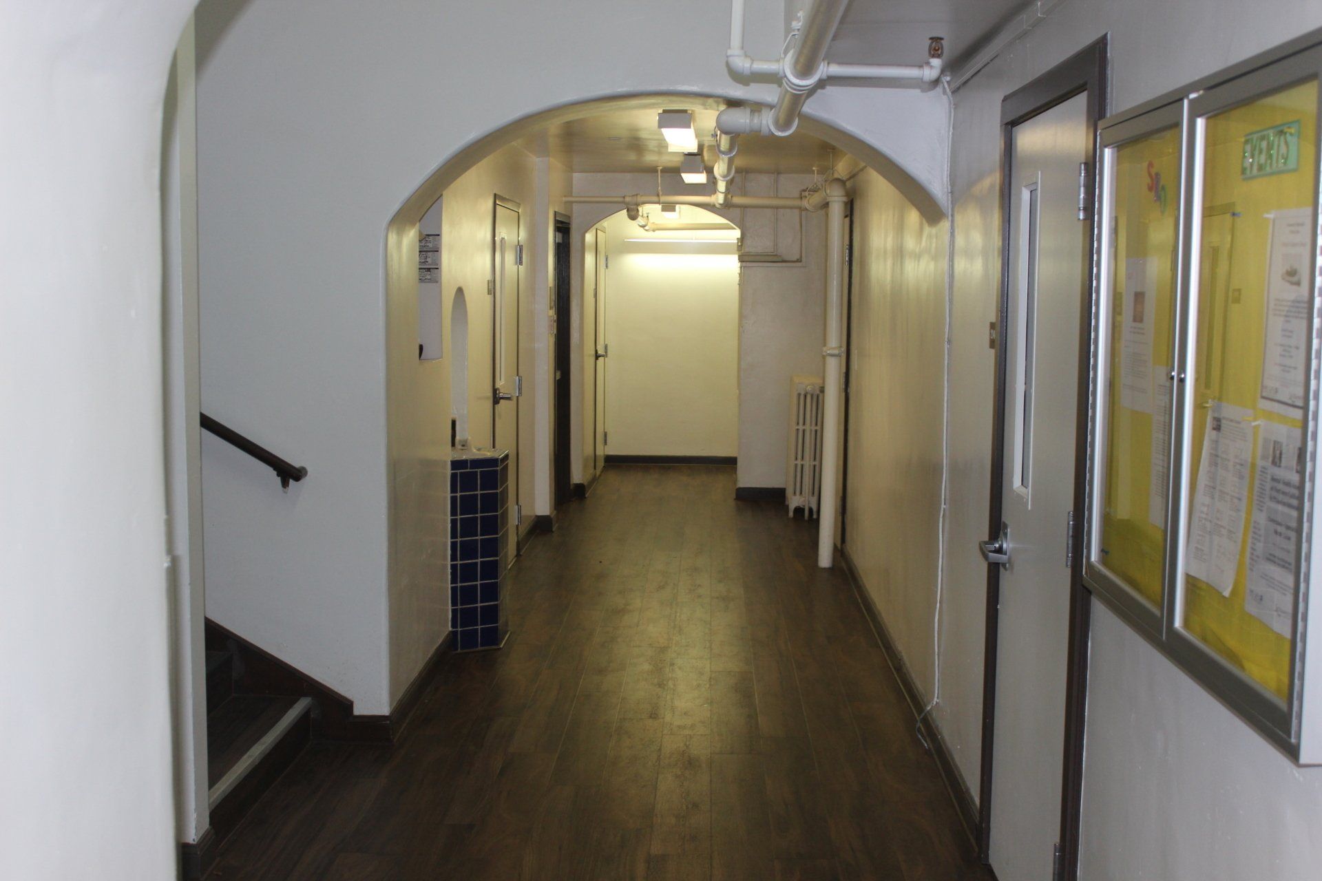 A long hallway with a bulletin board on the wall.