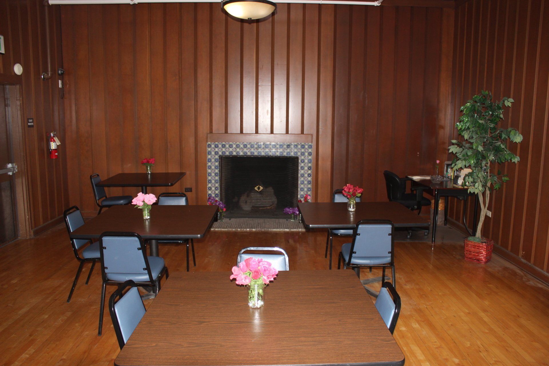 A room with tables and chairs and a fireplace.