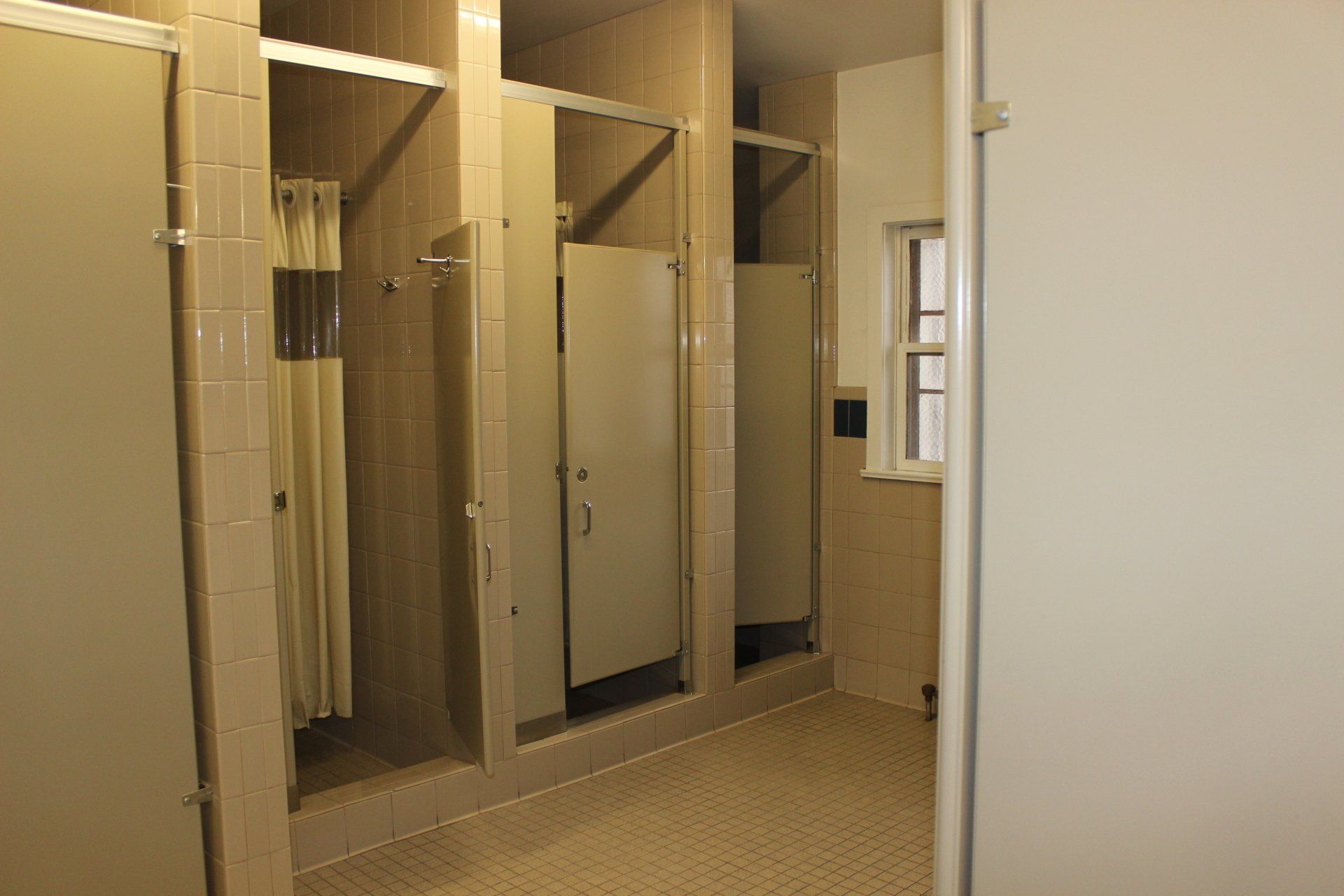 A bathroom with a lot of shower stalls and a window