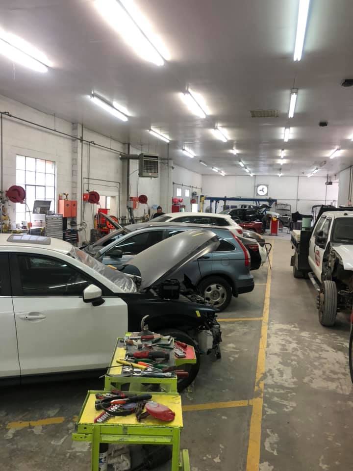 A row of cars are parked in a garage with their hoods up.