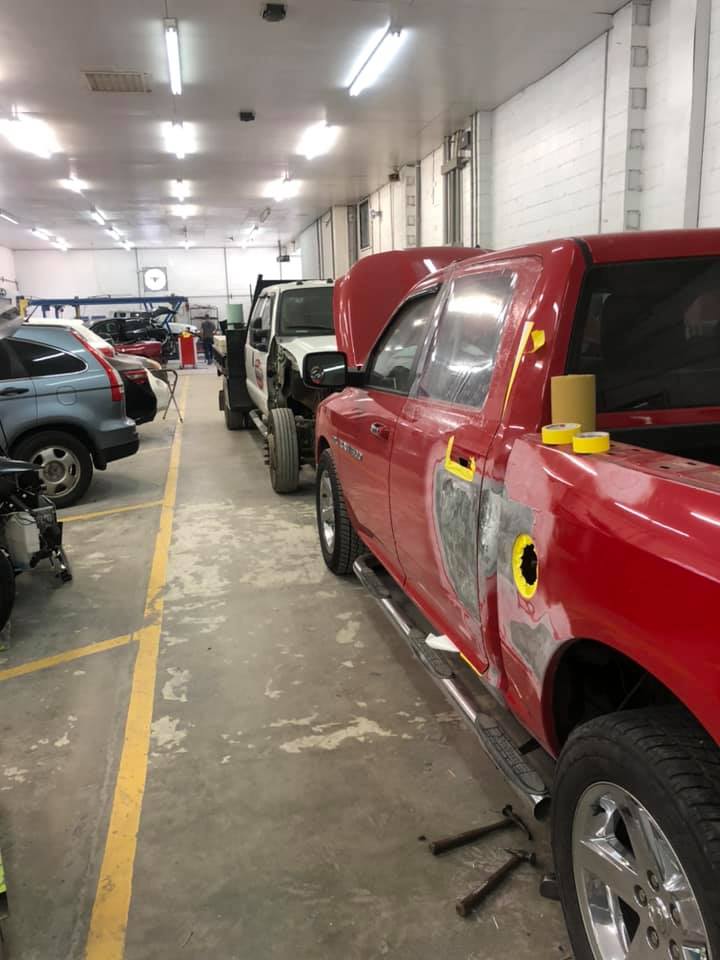 A red truck is sitting in a garage with other cars.