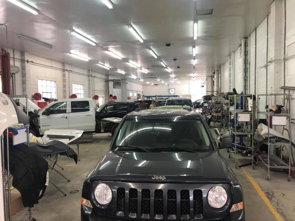 A black jeep is parked in a large garage.